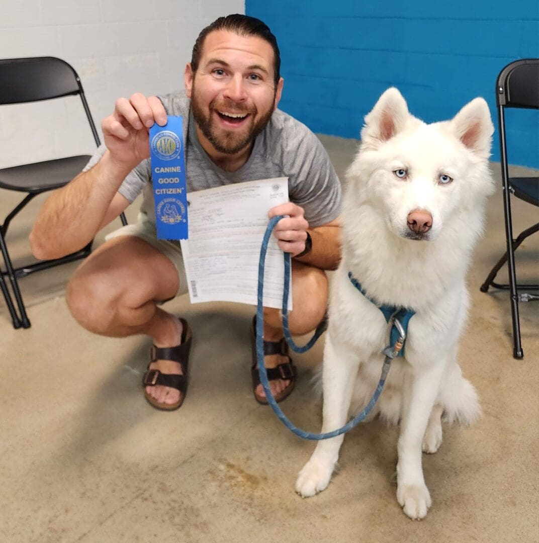 A man holding a blue ribbon and a white dog.