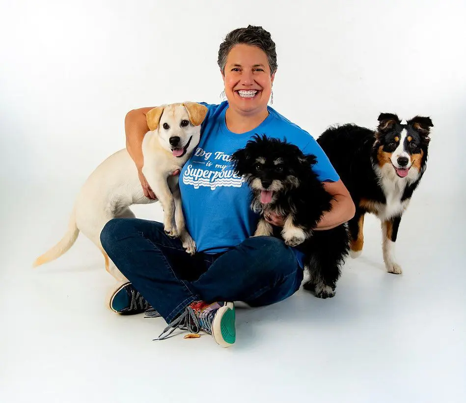 A woman sitting on the ground with two dogs.